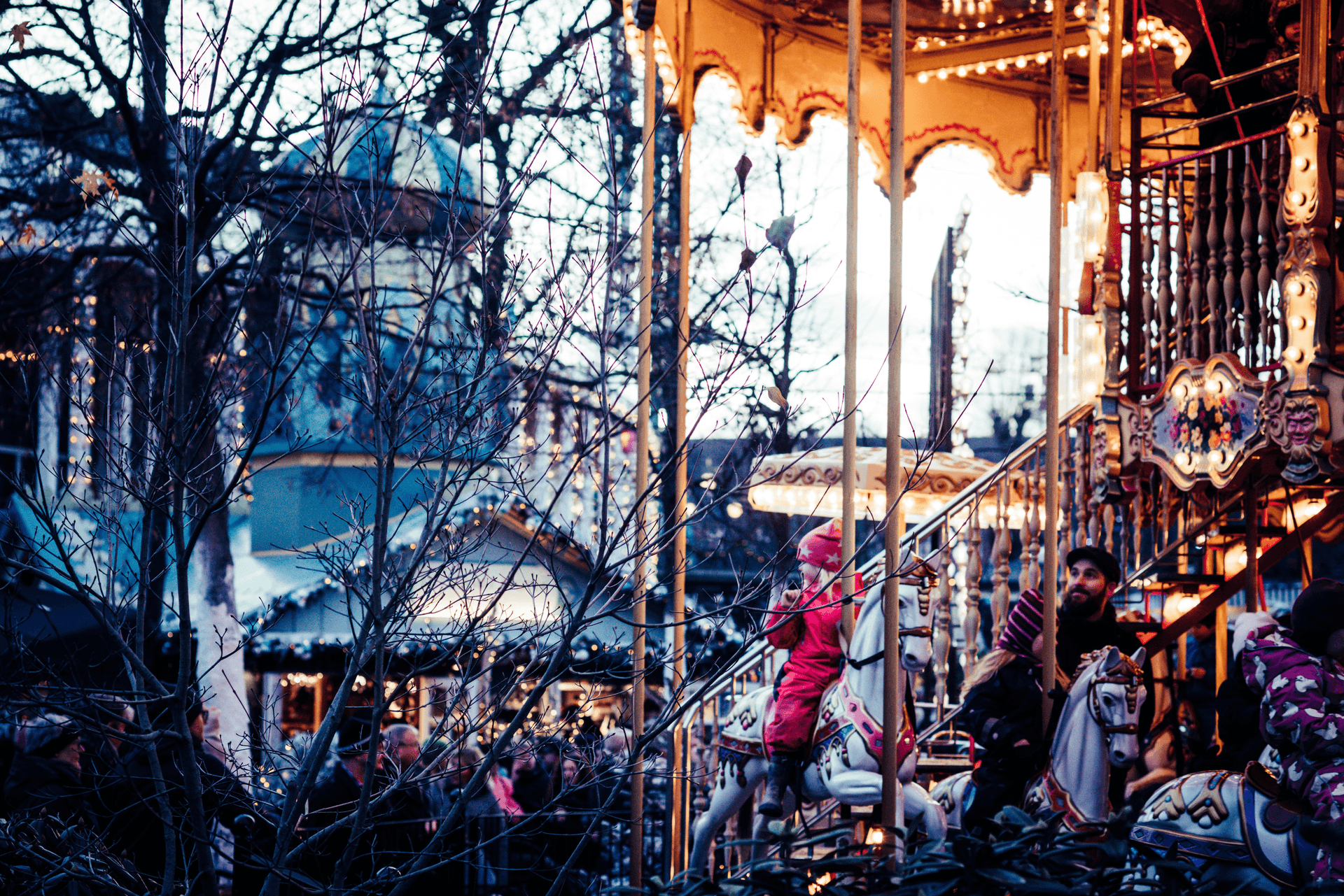 Child on a carousel at Tivoli Gardens, Copenhagen — warm lights in the early evening.
