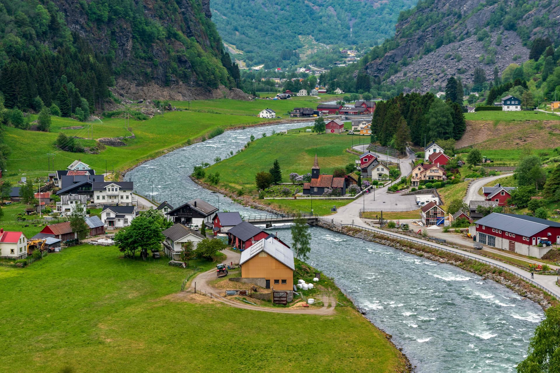 Small fjord village surrounded by mountains and river valley near Flåm, Norway.